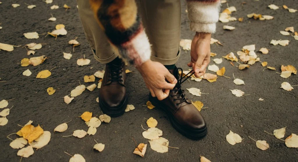 Woman wearing layered outfit with boots in autumn landscape
